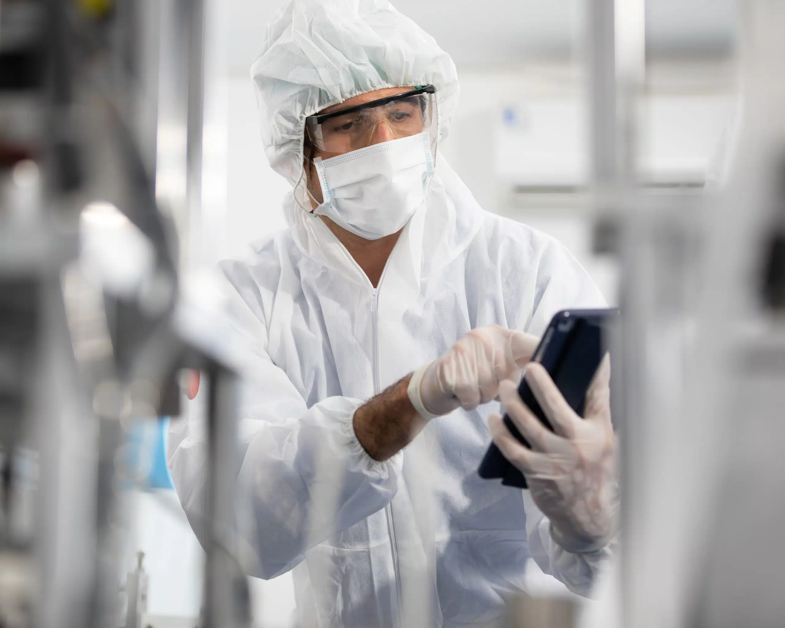 Life science worker in personal protective equipment accessing digitalized audit software on a tablet while in a lab