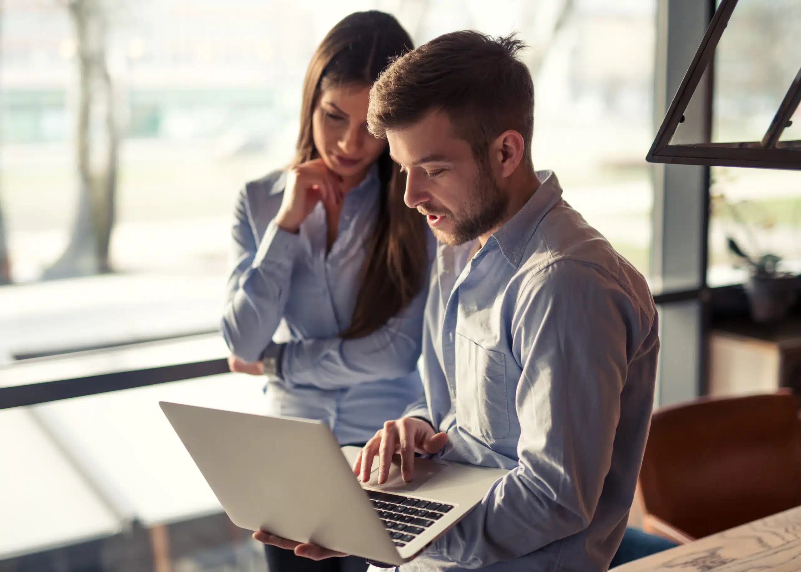 Two coworkers thoughtfully sharing information on complaints on a laptop