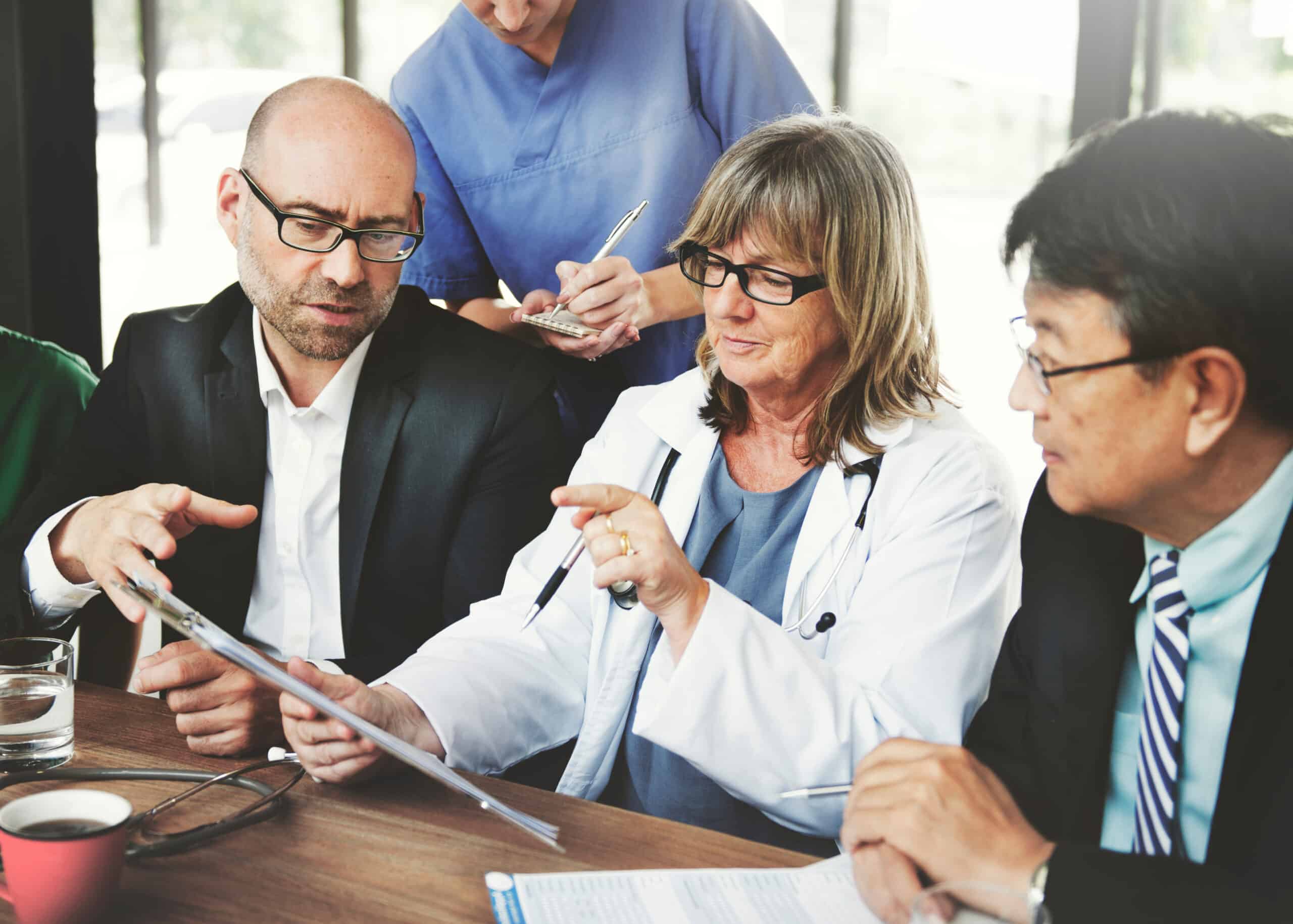 Coworkers, some in scrubs and others in business suits sharing information on complaints