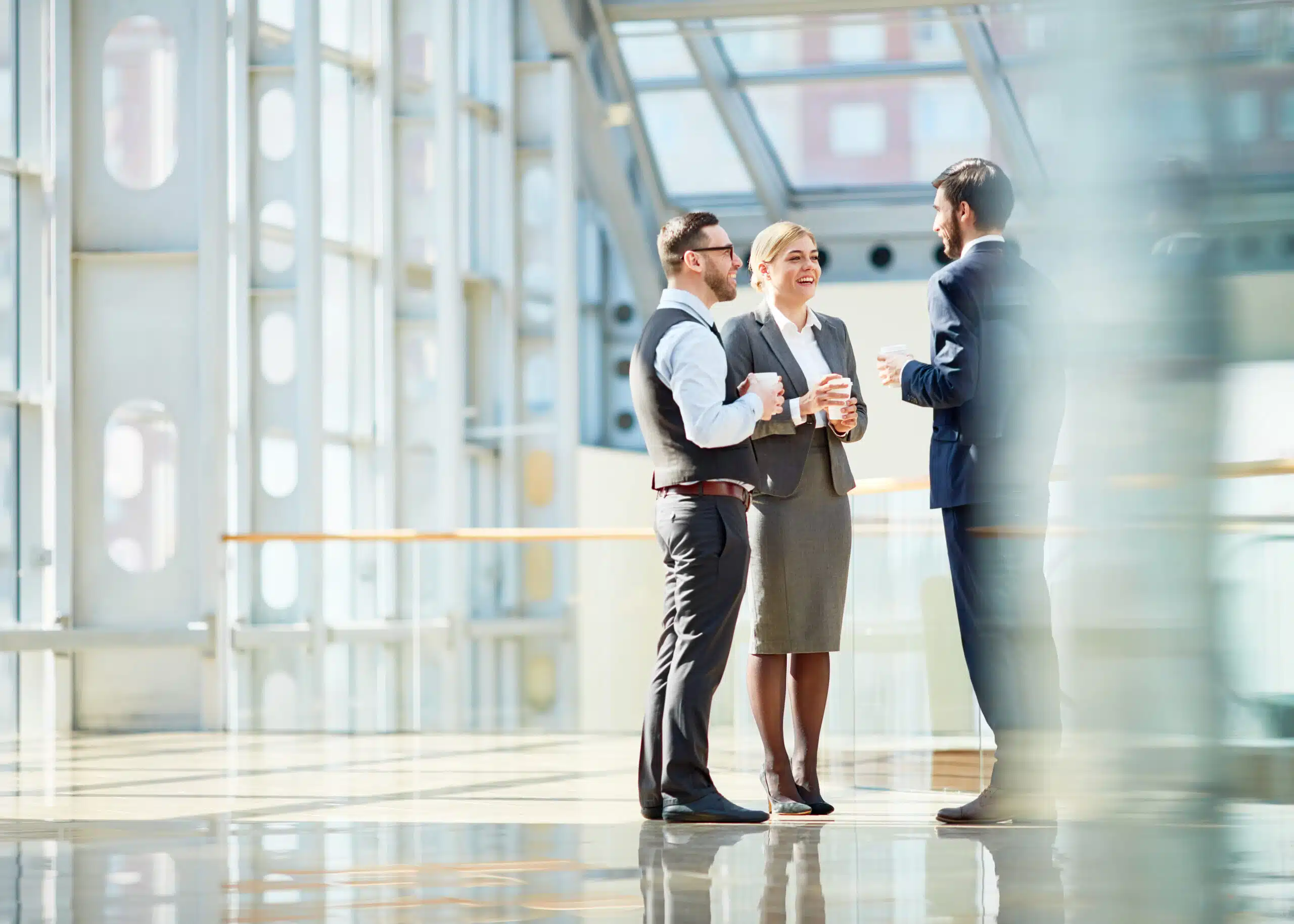 Auditors meeting over coffee in a lobby to discuss complaint management compliance