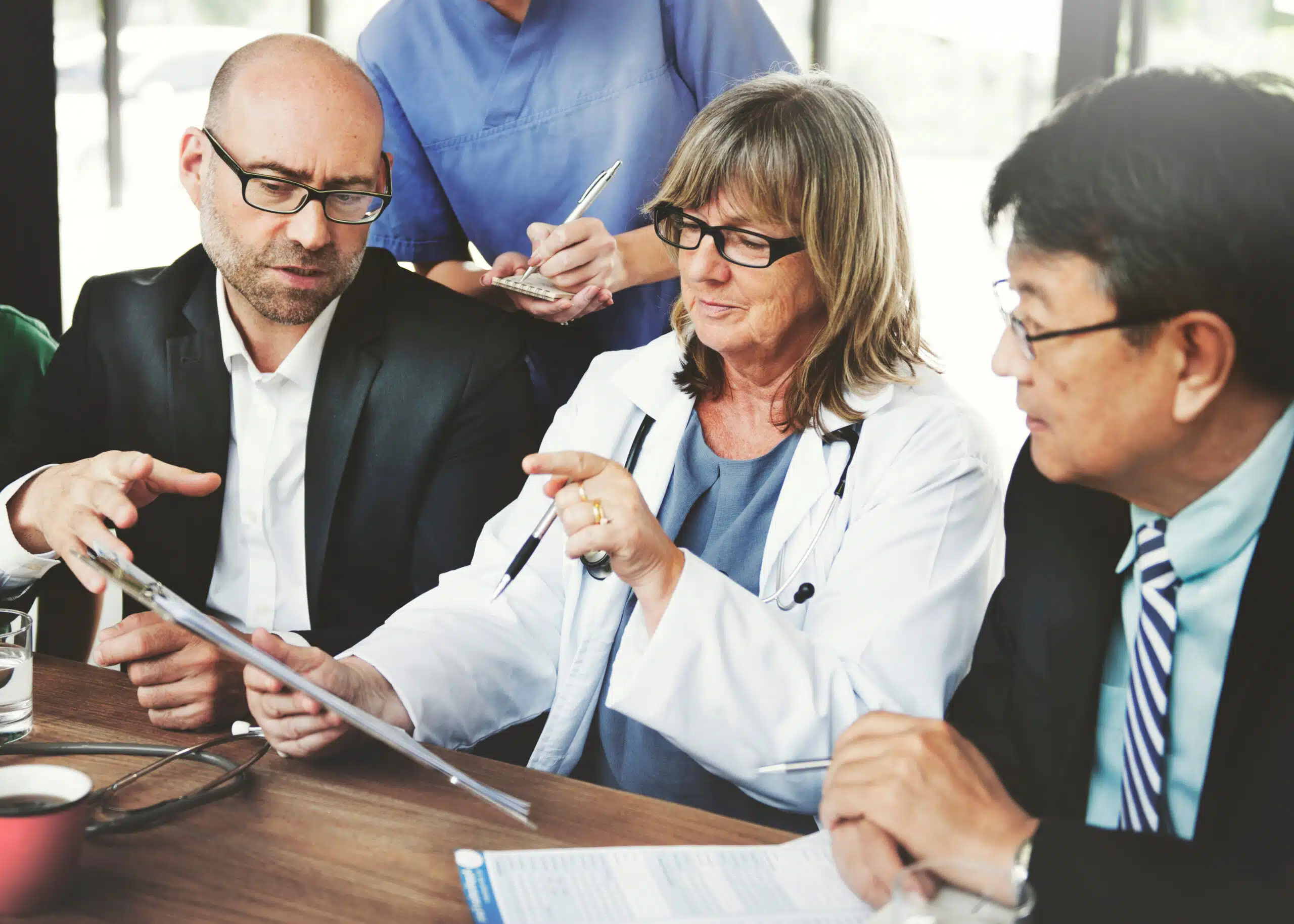 A group of people, some in business suits and others in scrubs collaborating on deviation management