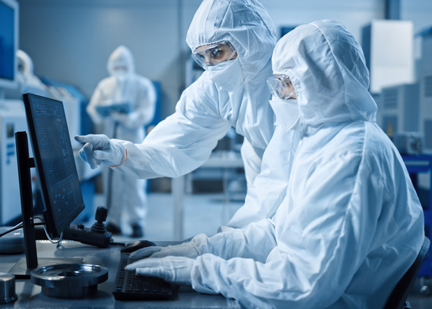 Two workers in personal protective gear sitting and pointing at clear deviation data on a computer