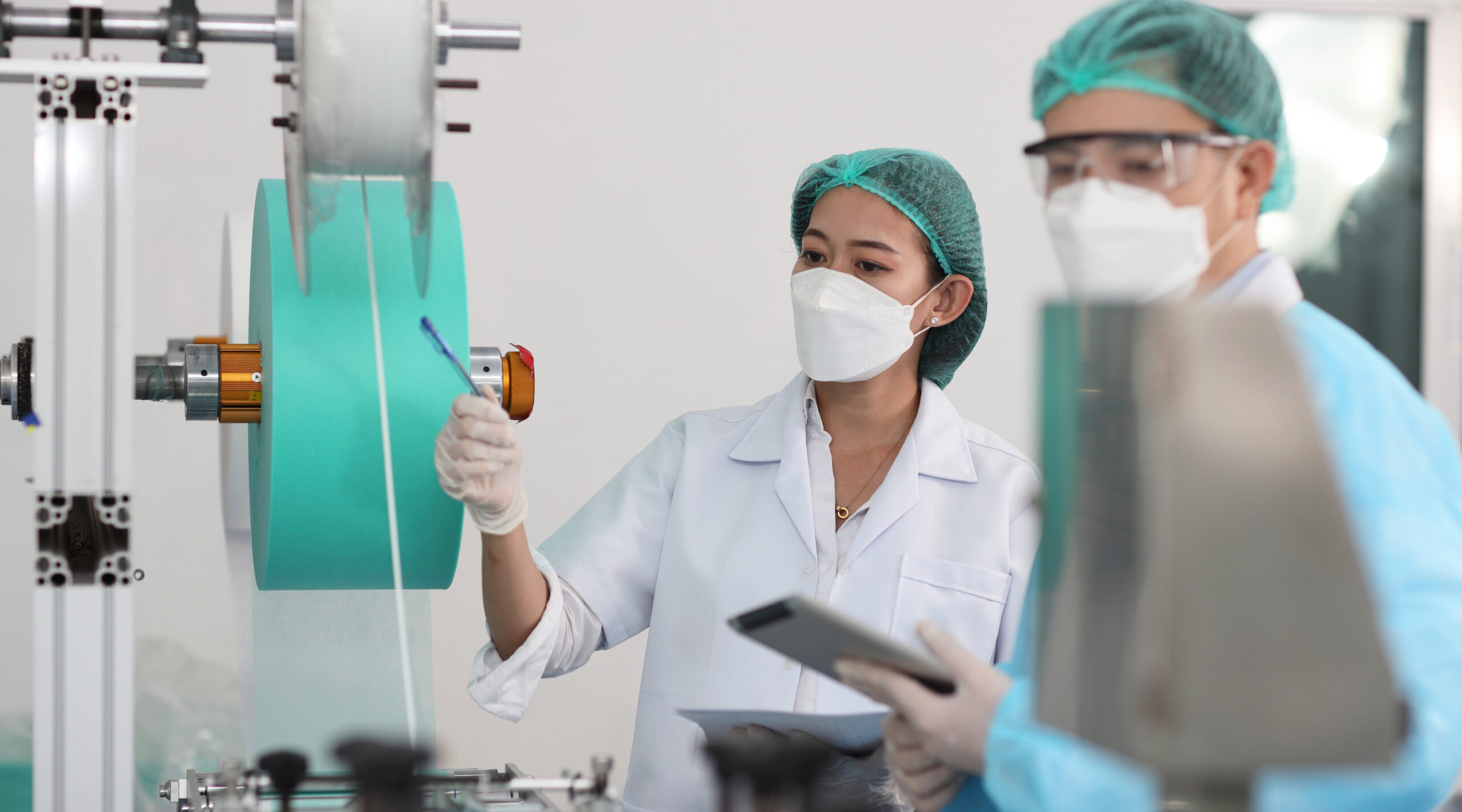 Two workers in personal protective gear pointing at machinery to investigate a deviation