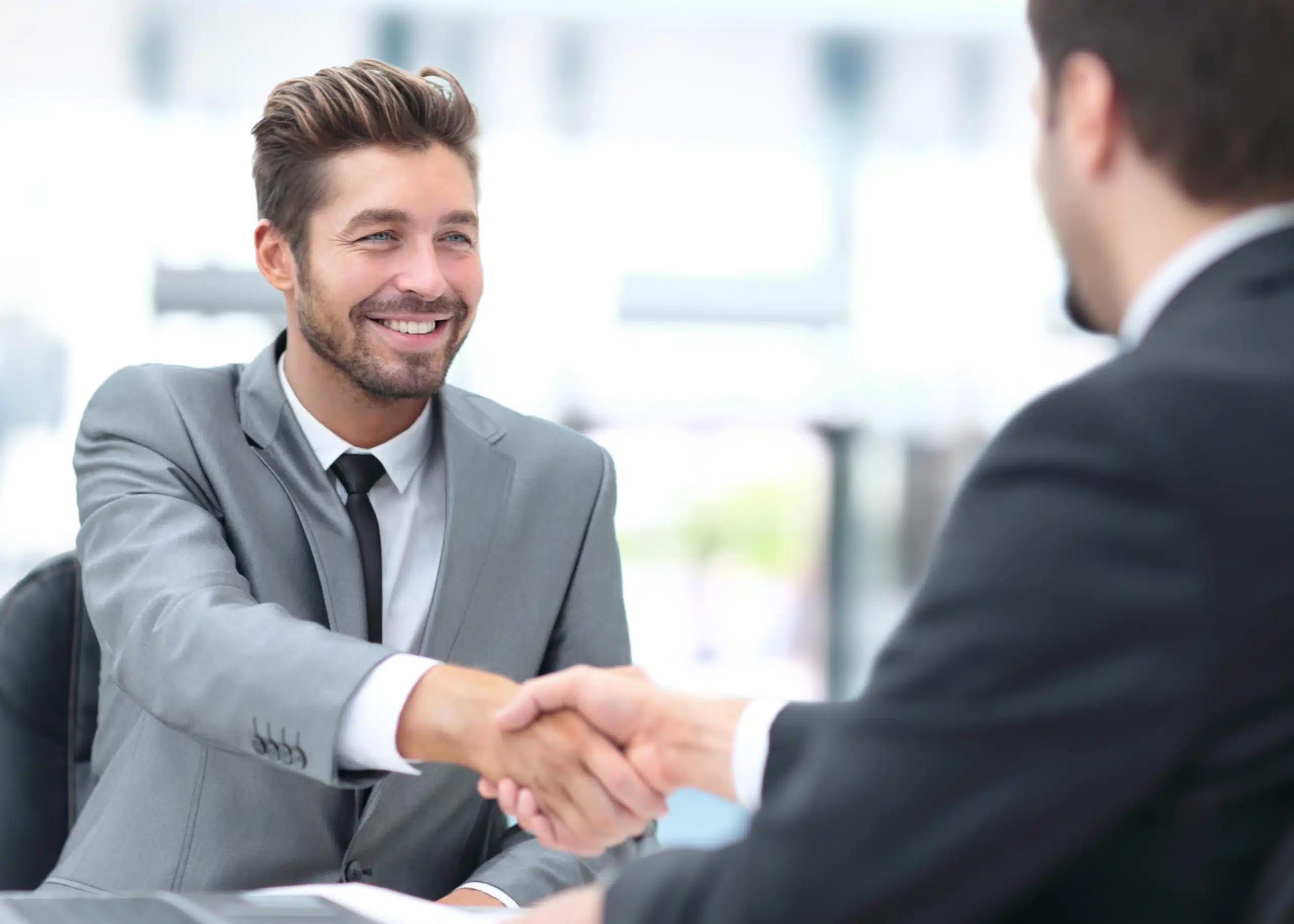 Two business men smiling and shaking hands