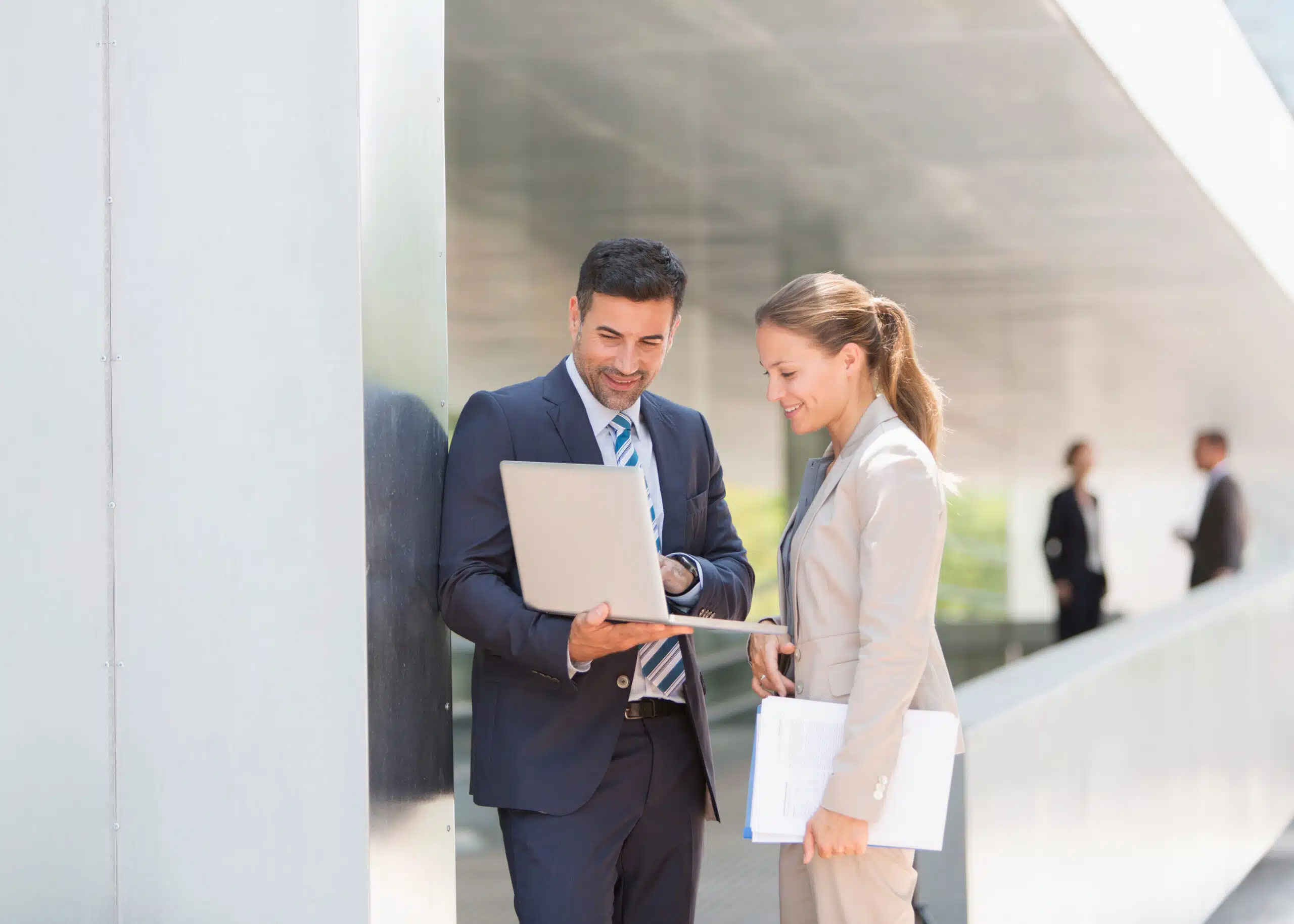 Two compliance workers in suits looking at a digital record of nonconformance tracking on a computer