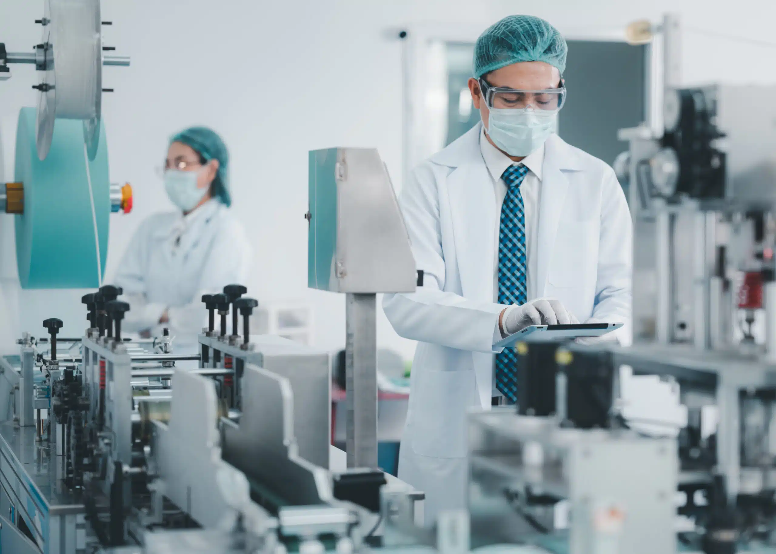 A man in a lab coat logging a nonconformance on site in a medical device production plant on a tablet