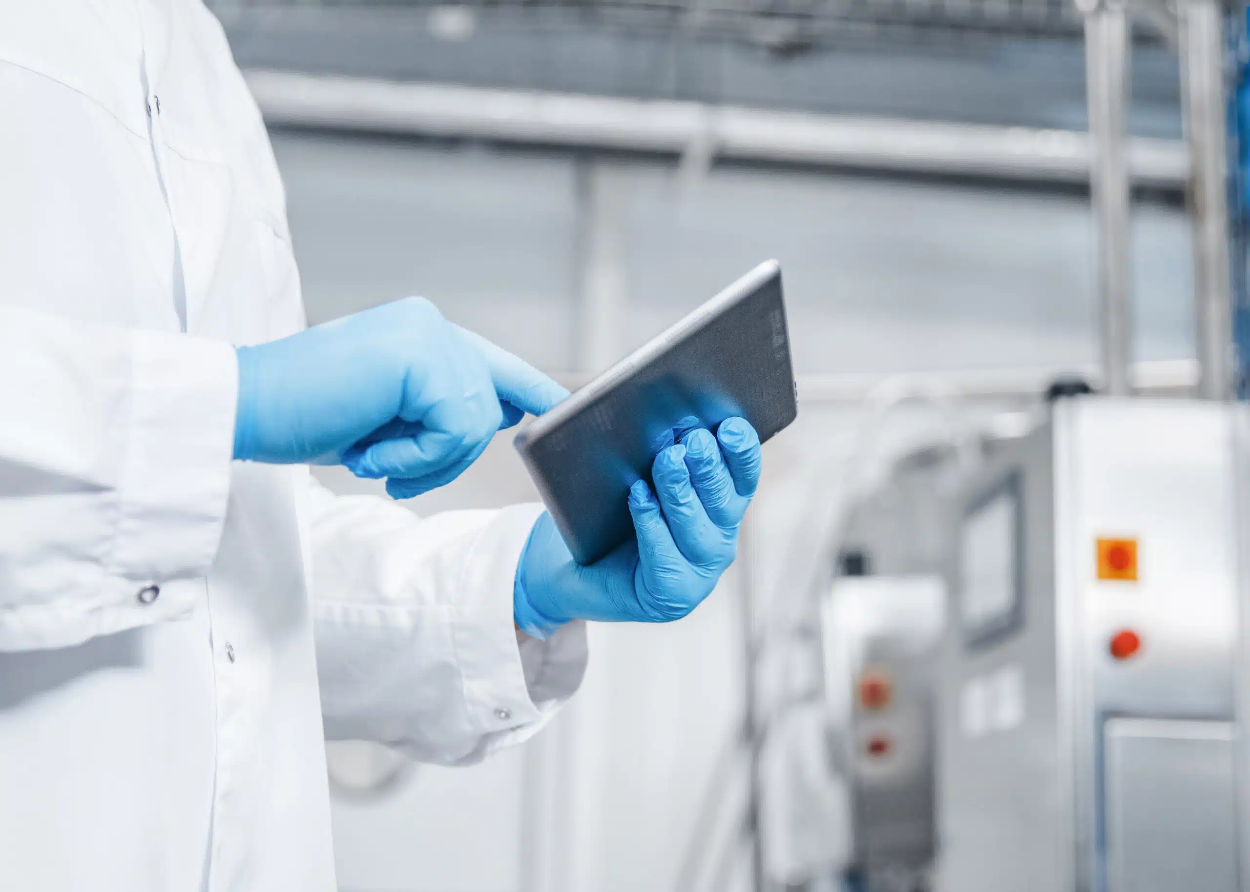 Hands with rubber gloves using a tablet in a pharmaceutical production facility