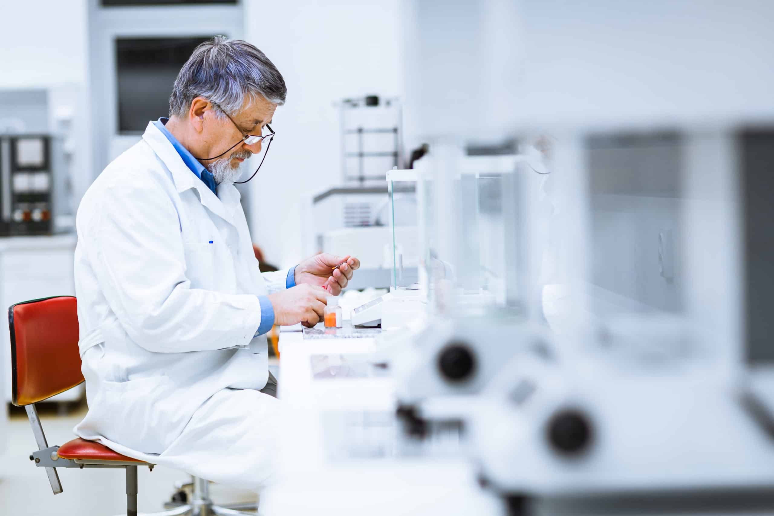 A man siting at a desk testing a pharmaceutical batch for specifications