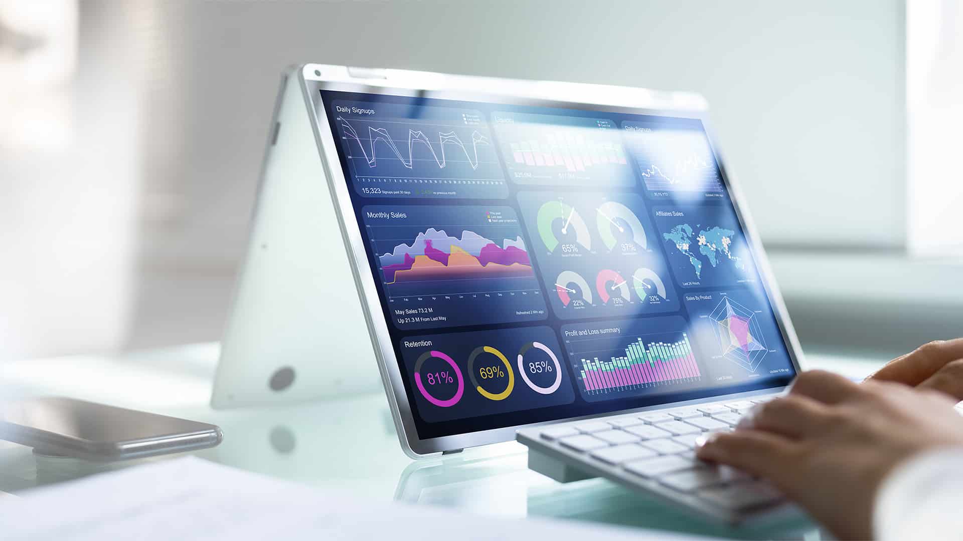A close up of hands using a tablet that shows various graphs and data